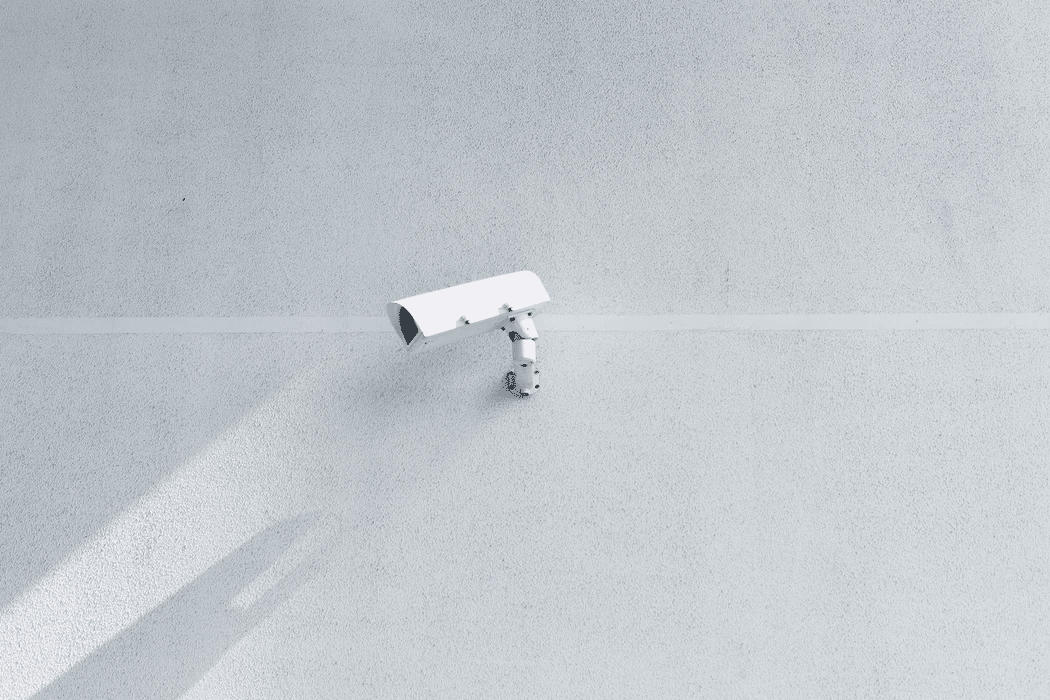 A security camera on a white wall 