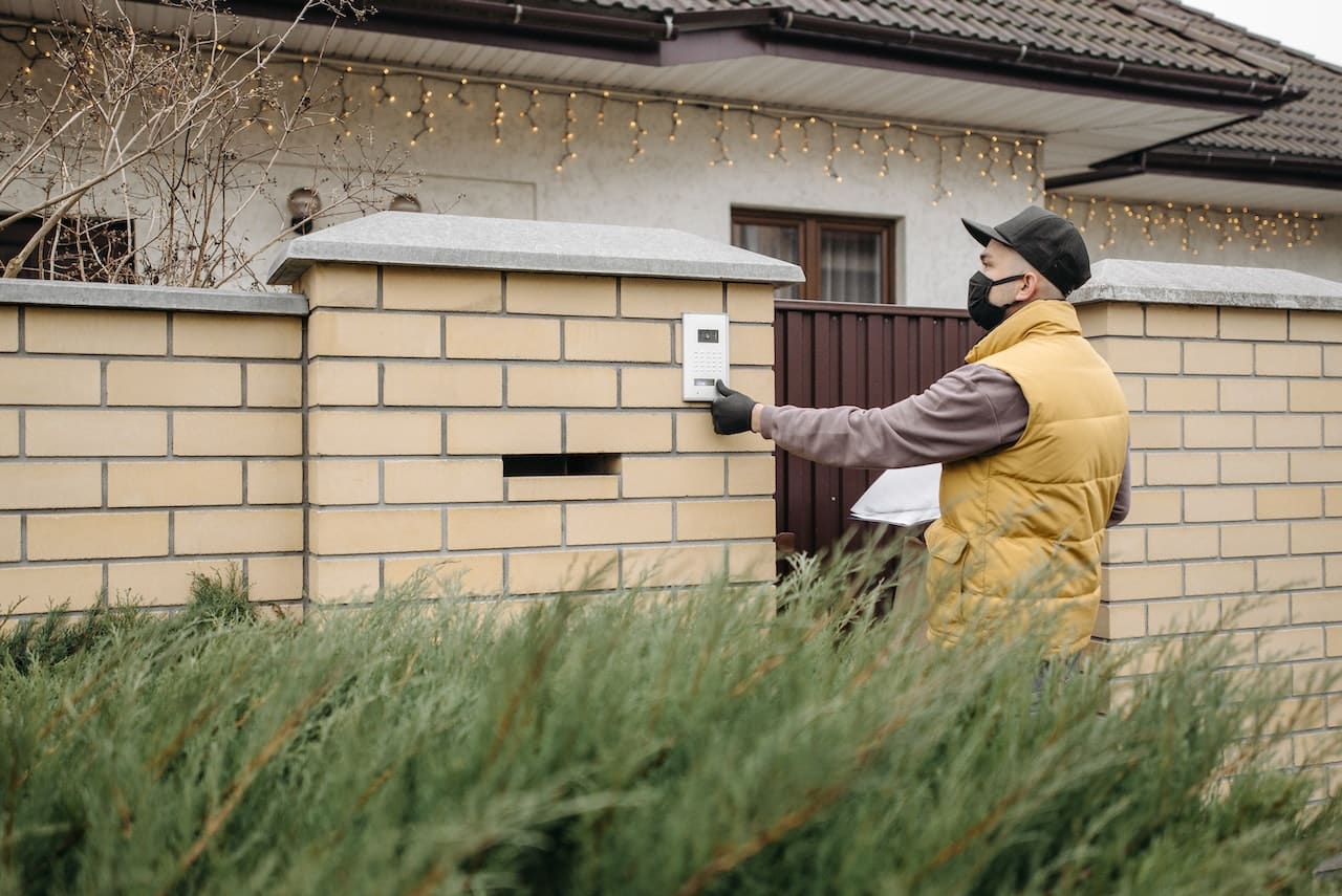 delivery man pressing a home security touch pad.