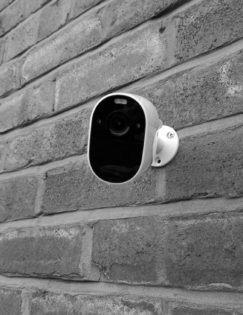 A security camera mounted on a gray brick wall