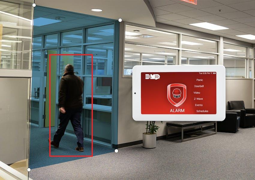 A man walking through a hallway with a red rectangle around him and a device with an alarm on the screen floating in the air