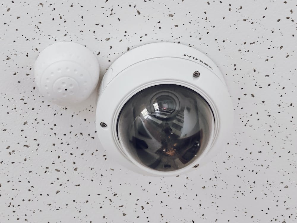 a round white security camera mounted on a ceiling